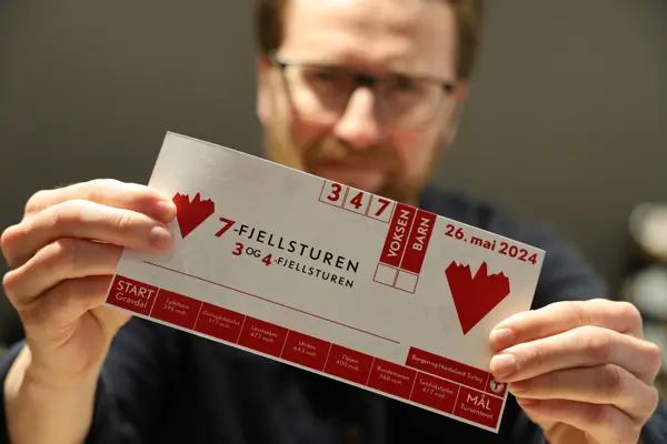 Mann viser frem startkort til 7-fjellsturen.