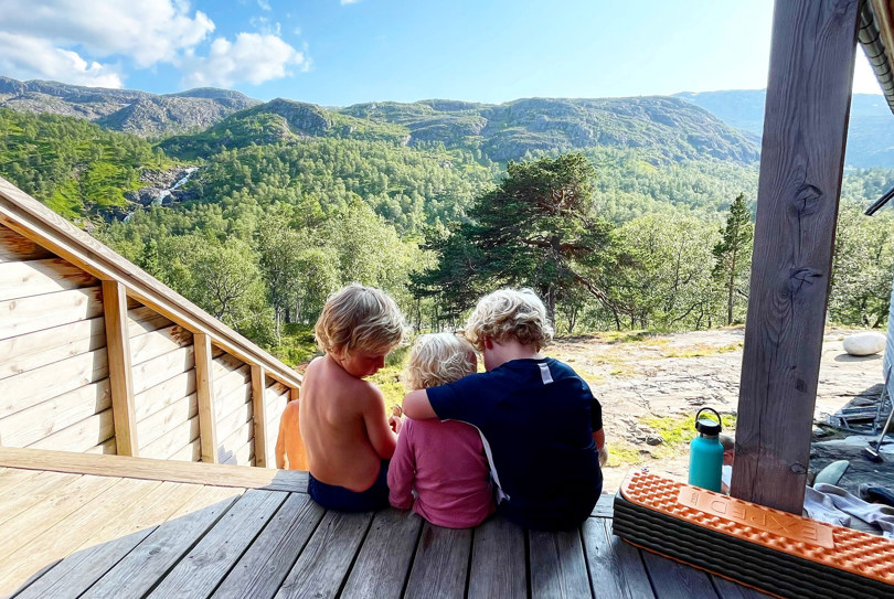 tre barn sitter på hyttetrapp og holde rundt hverandre