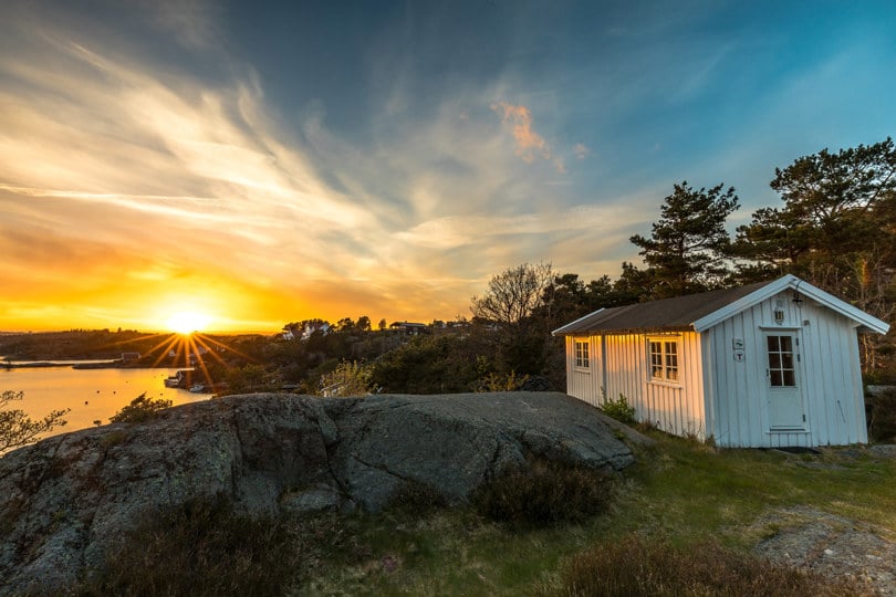 hvit hytte ved sjøen i solnedgang
