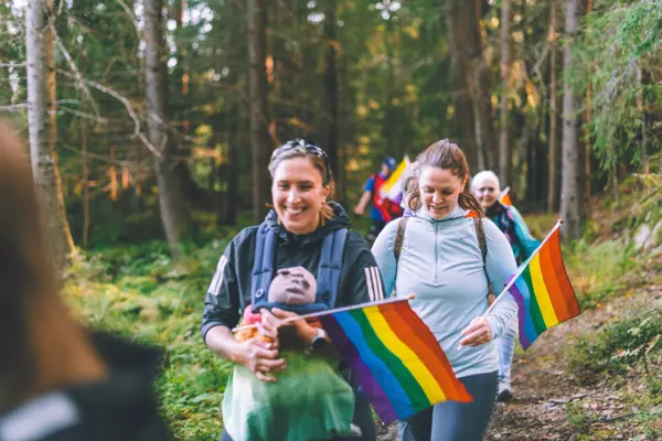 Mennesker på tur i skogen med regnbueflagg