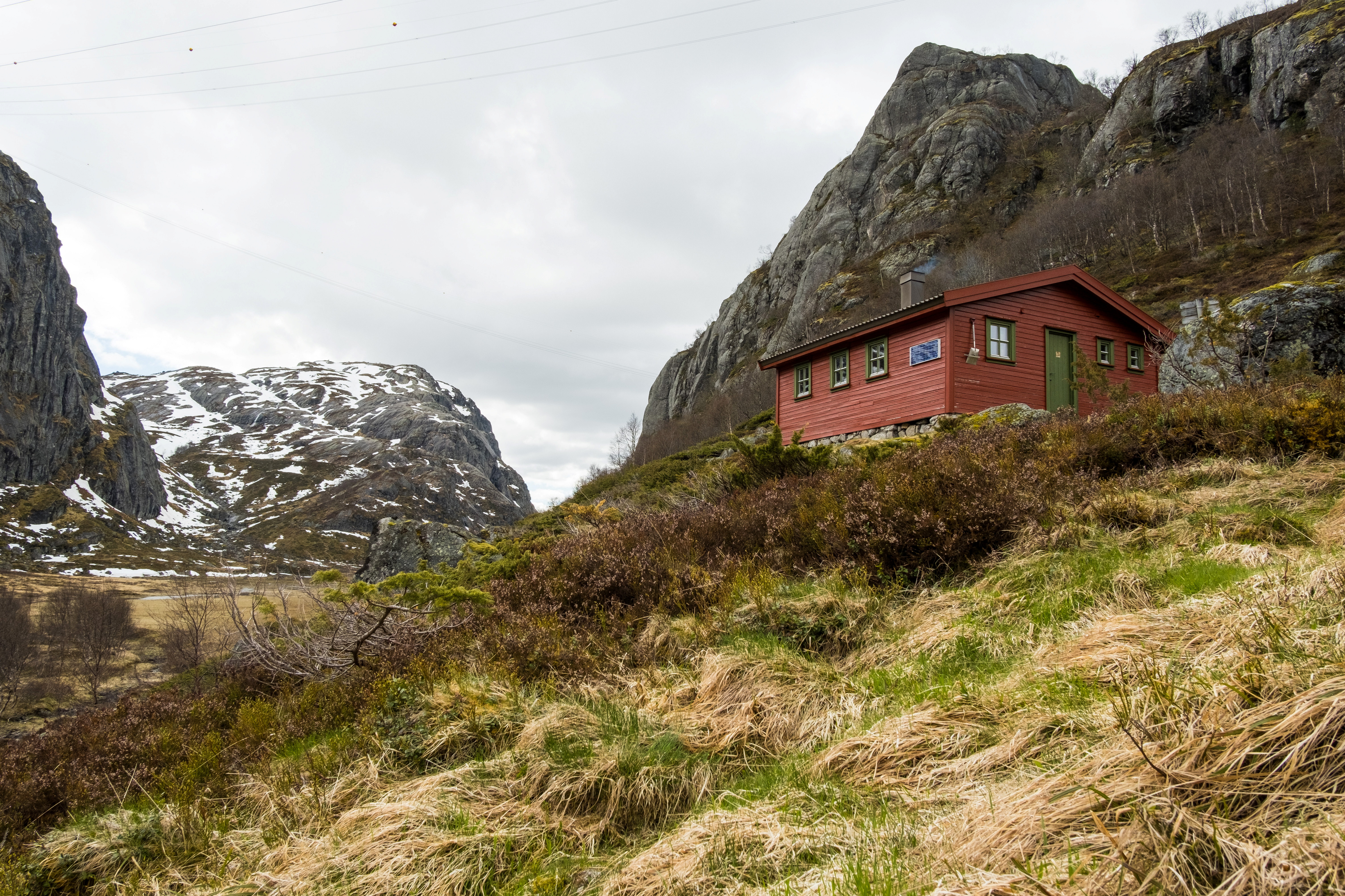 En rød hytte omgitt av fjell