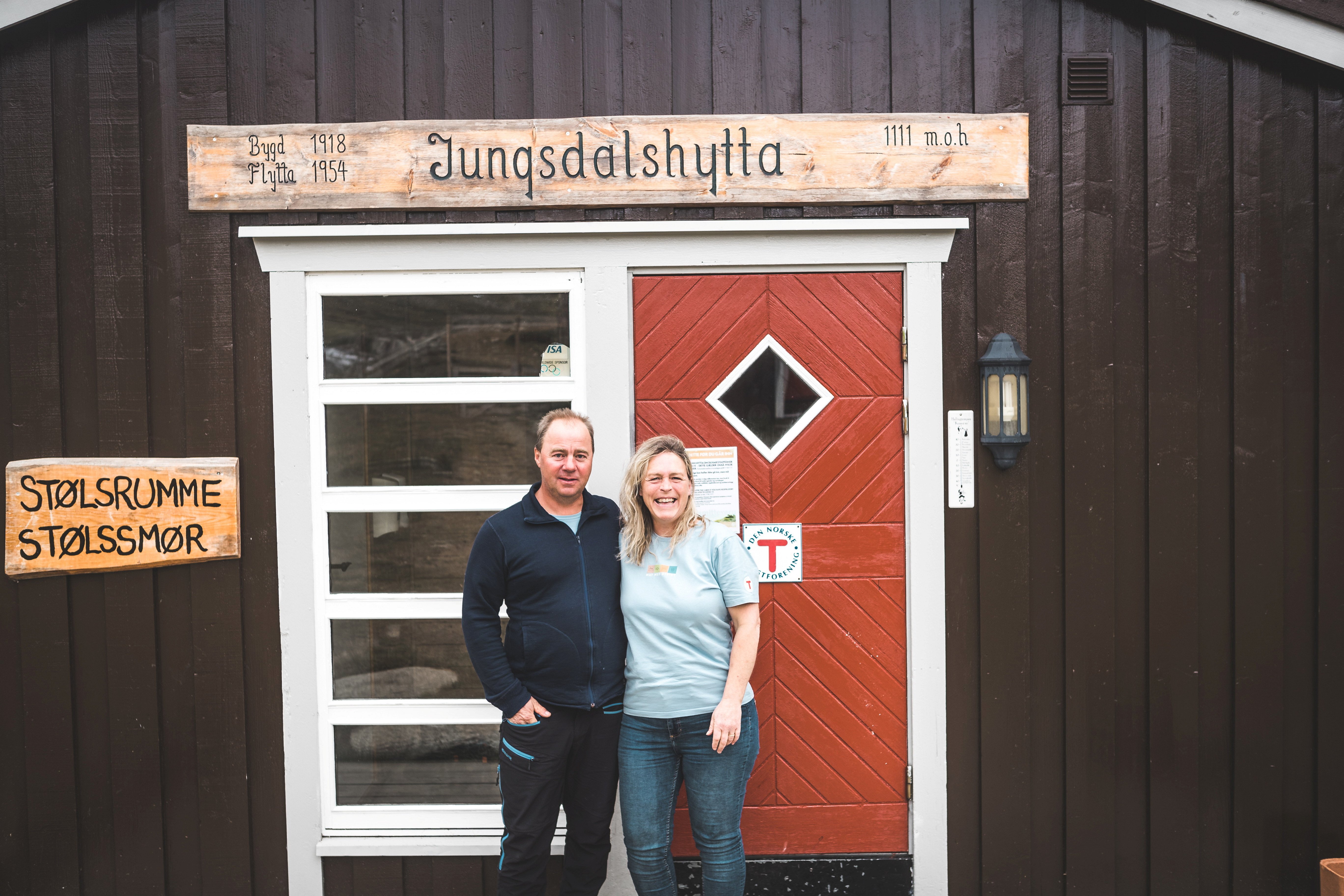 En mann og en dame som står utenfor en svart hytte