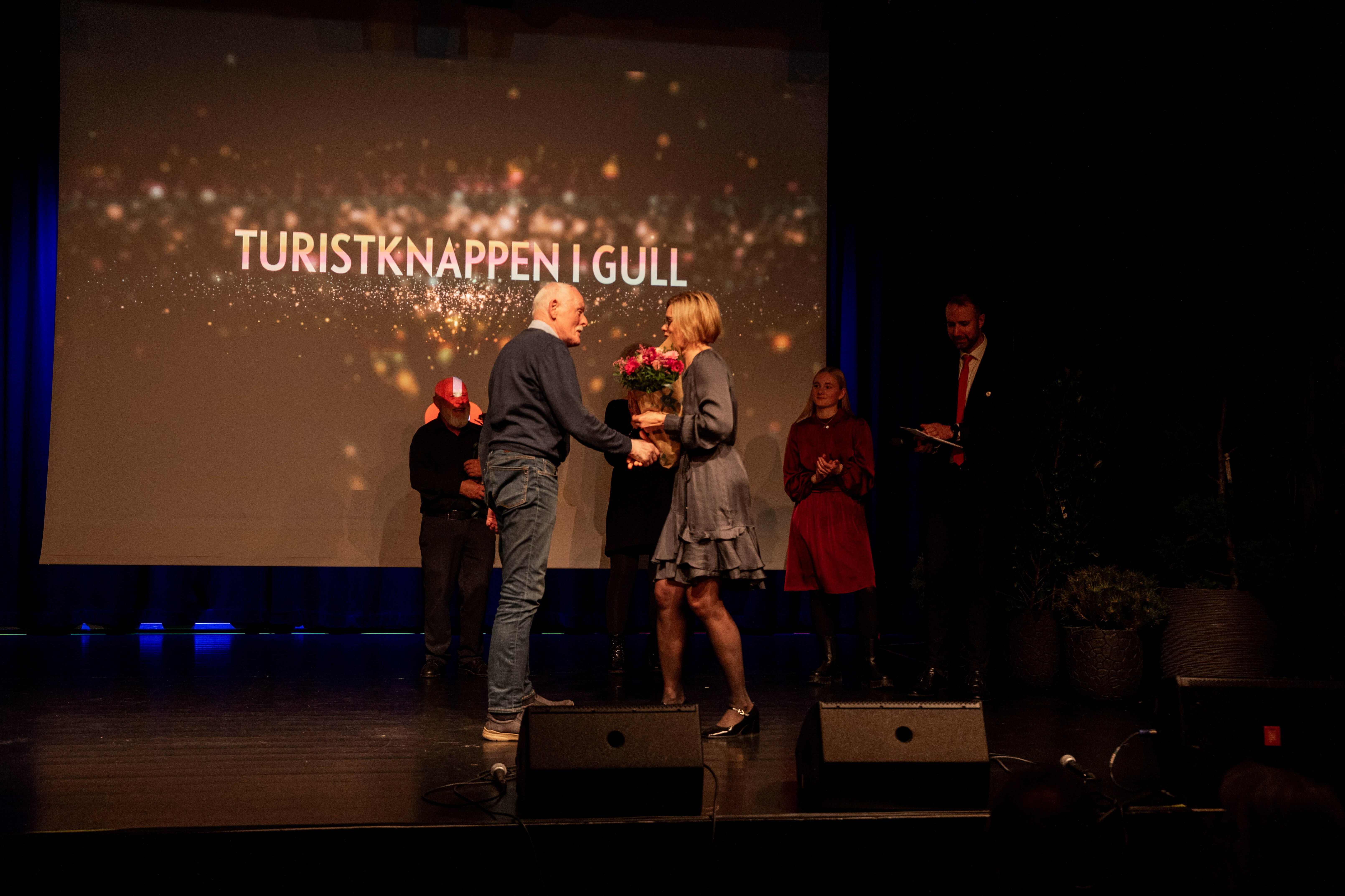 En mann mottar en pris på en scene