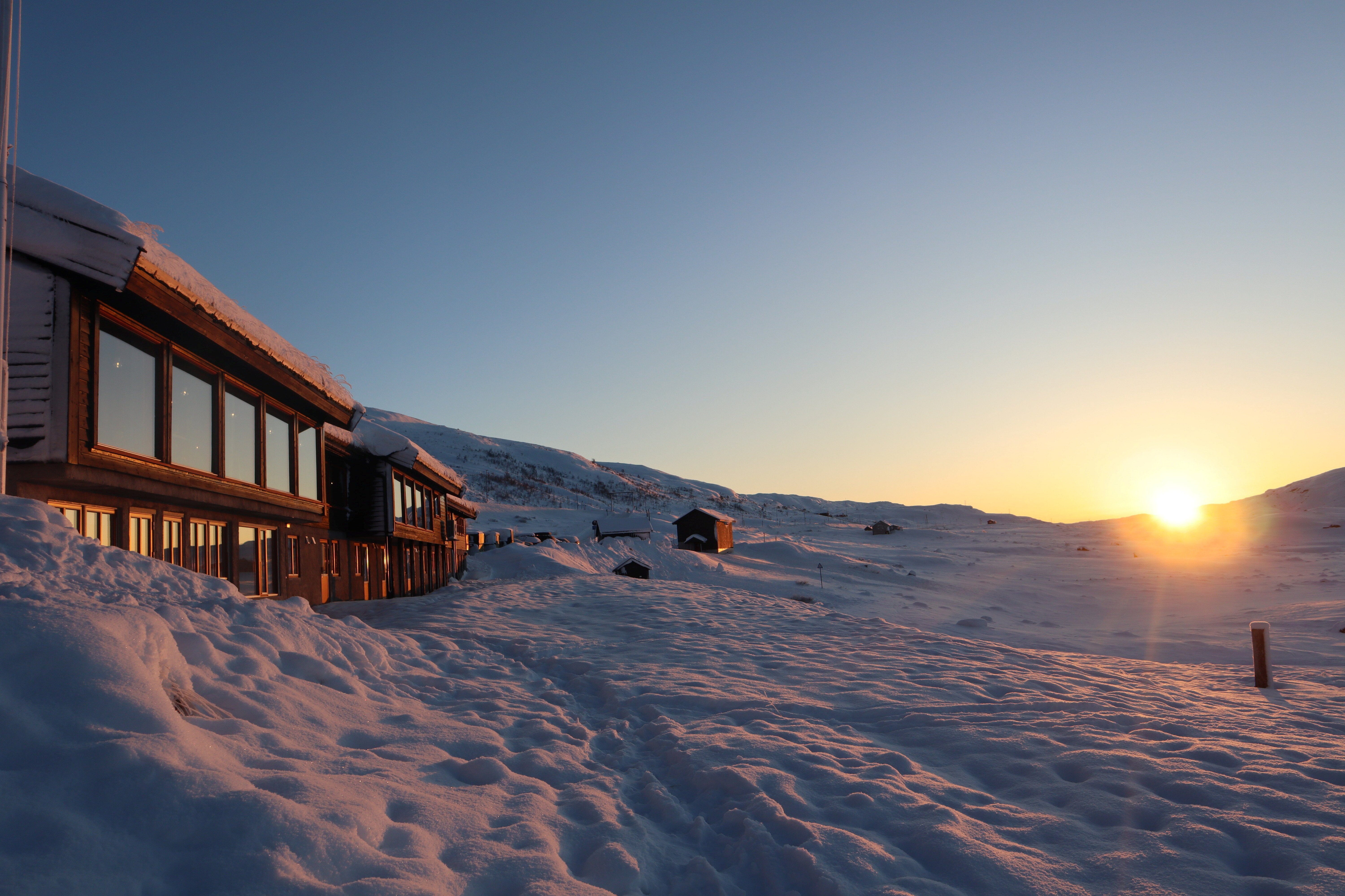 Hytte i solnedgang med snø rundt.