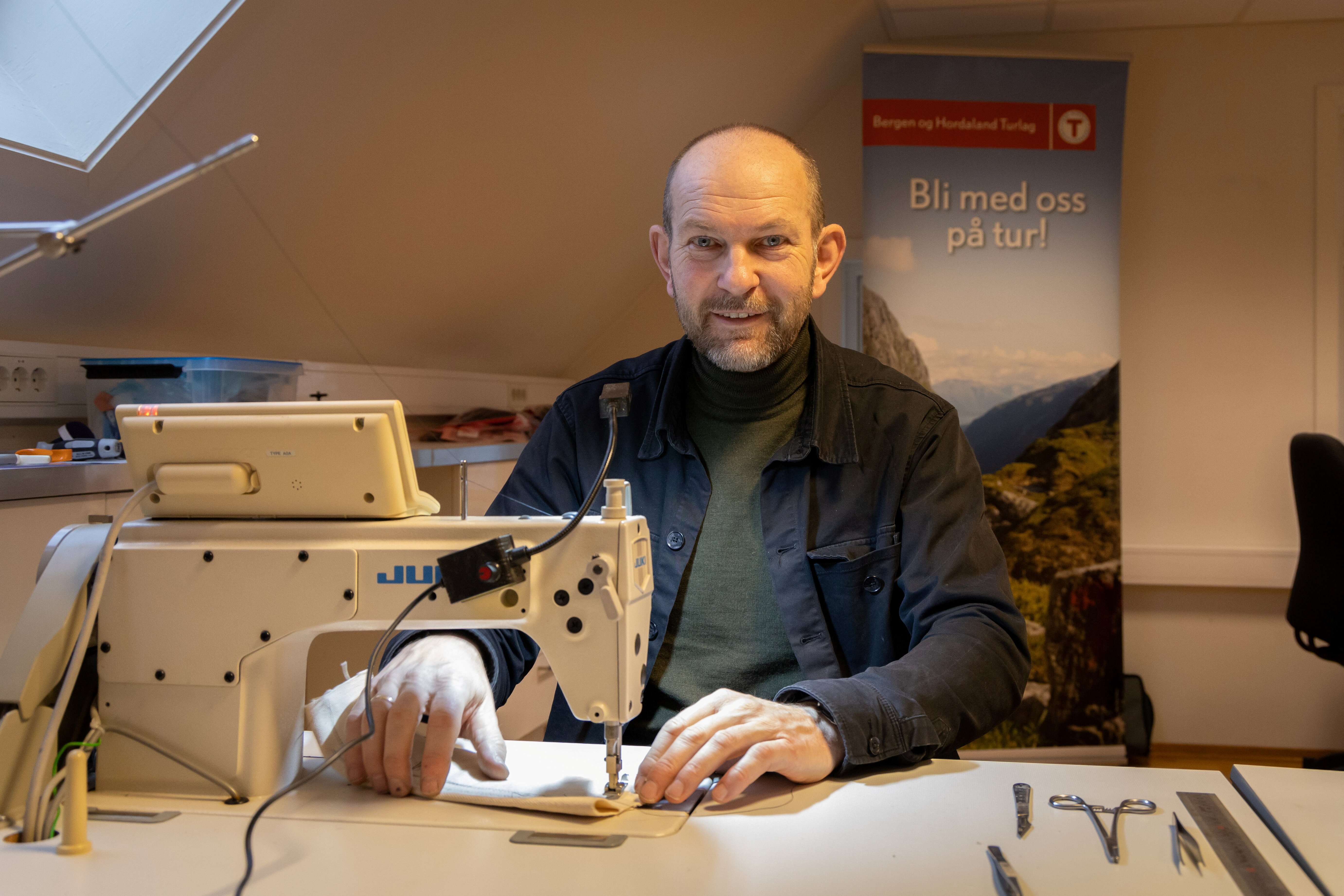 Mann sitter ved symaskin