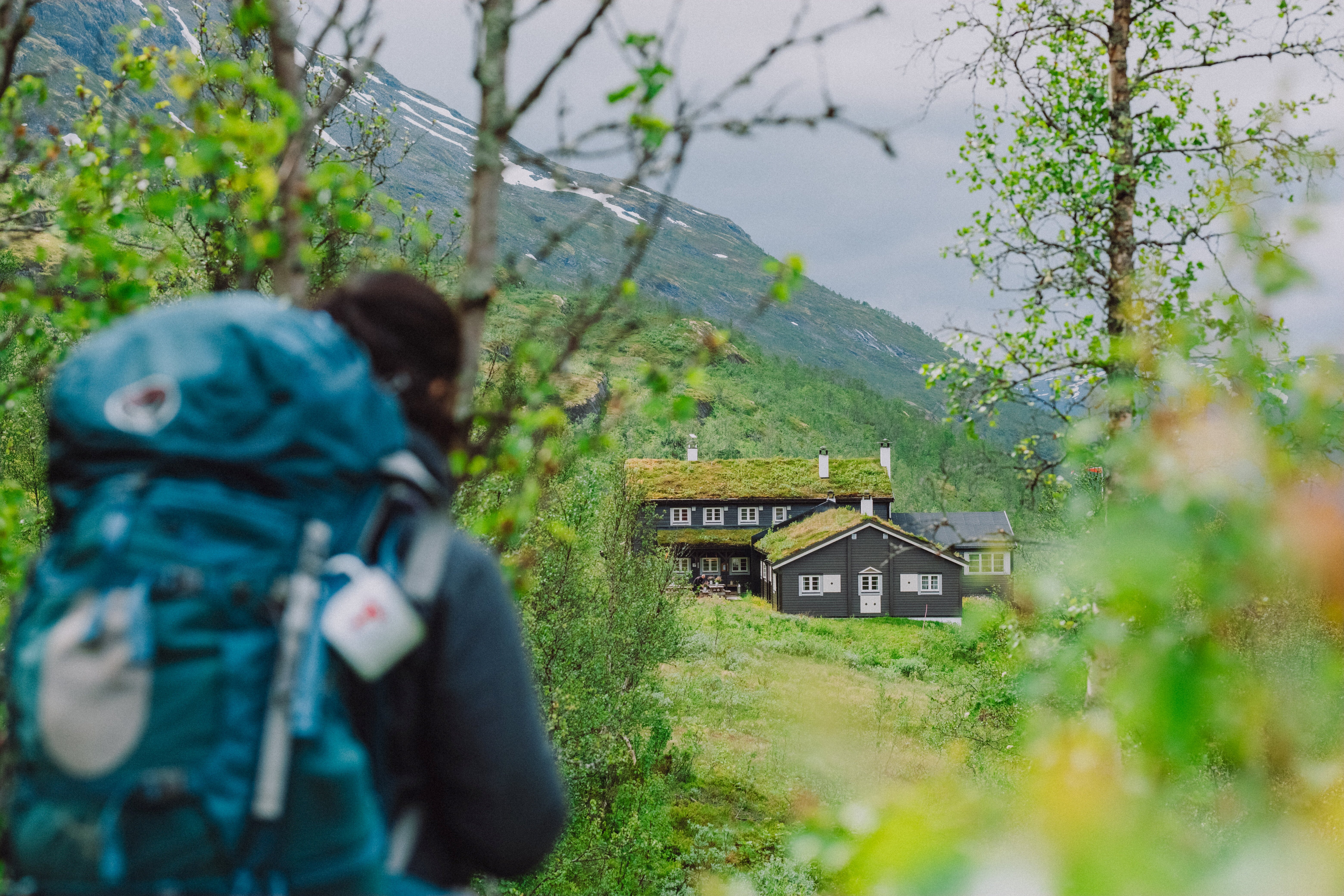person som står utenfor en hytte i fjellet