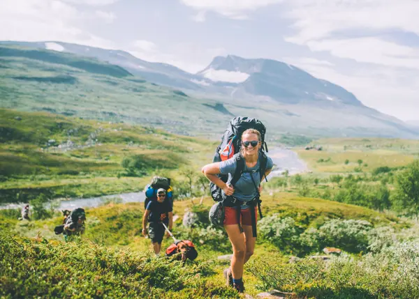 Smilende dame med tursekk på fjelltur