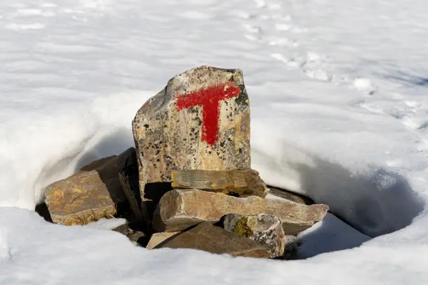 Varde i vårsnø med rød T malt på ene steinen.