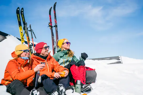 Tre personer sitter i snøen