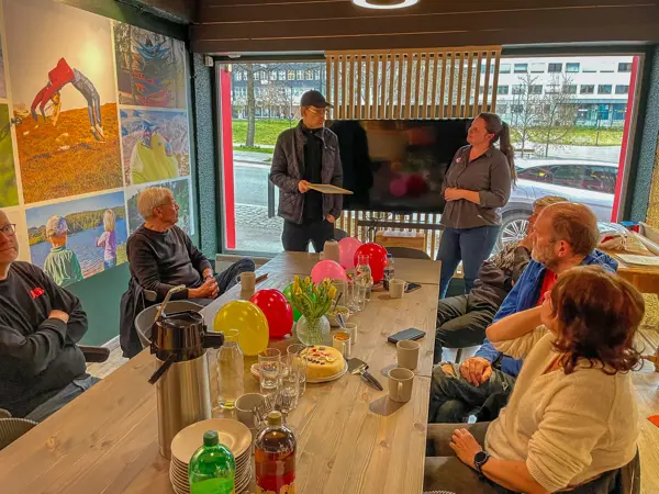 Mennesker samlet rundt et bord på et møterom med ballonger på bordet