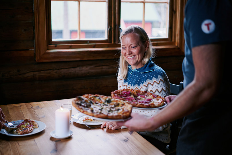 En dame som får servert pizza