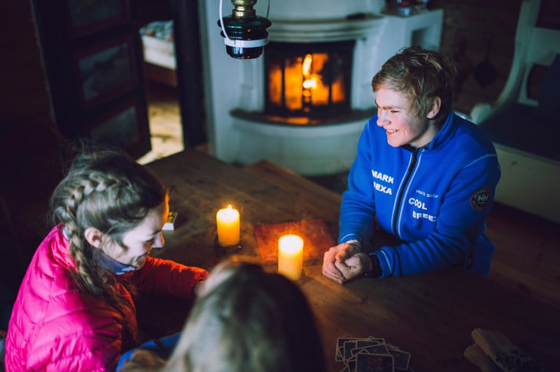 Tre ungdommer spiller kort på hyggelig DNT-hytte