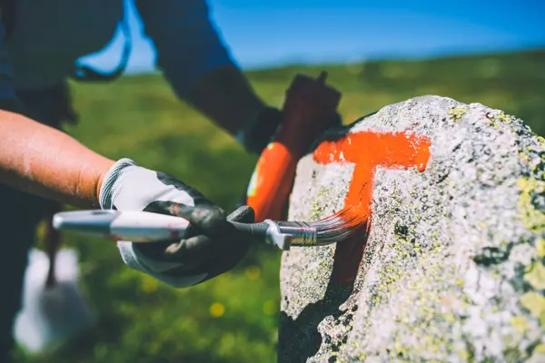 Rød T males på stein i fjellheimen