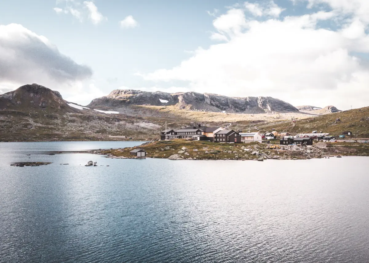 En svartmalt hytte i fjellet sommer ligger ved sjøen .