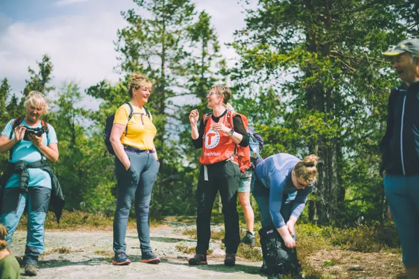 Mennesker på tur i skogen med DNT som smiler og ler