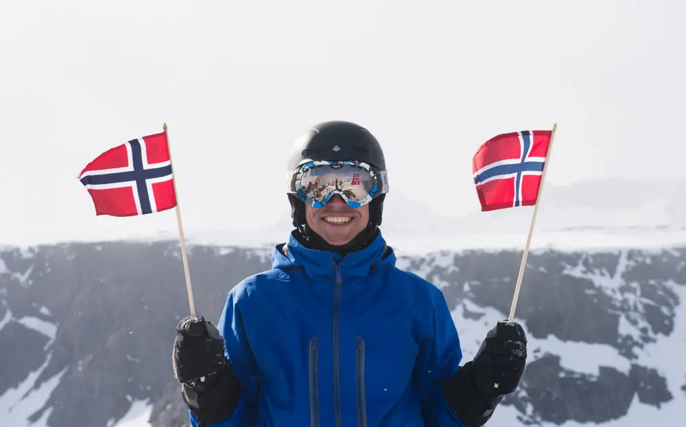 Morten F. Smedsrud jubler med norske flagg på toppen av Rasletind.