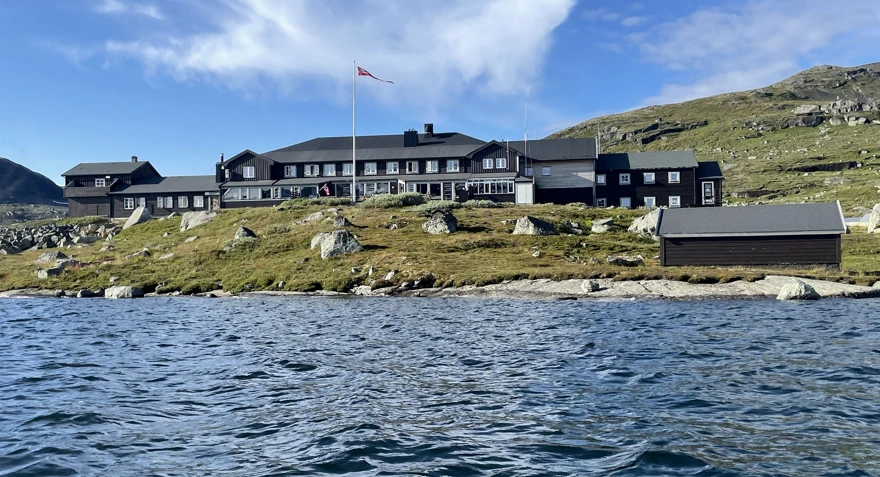 Svartmalt hytte i sommer sol.