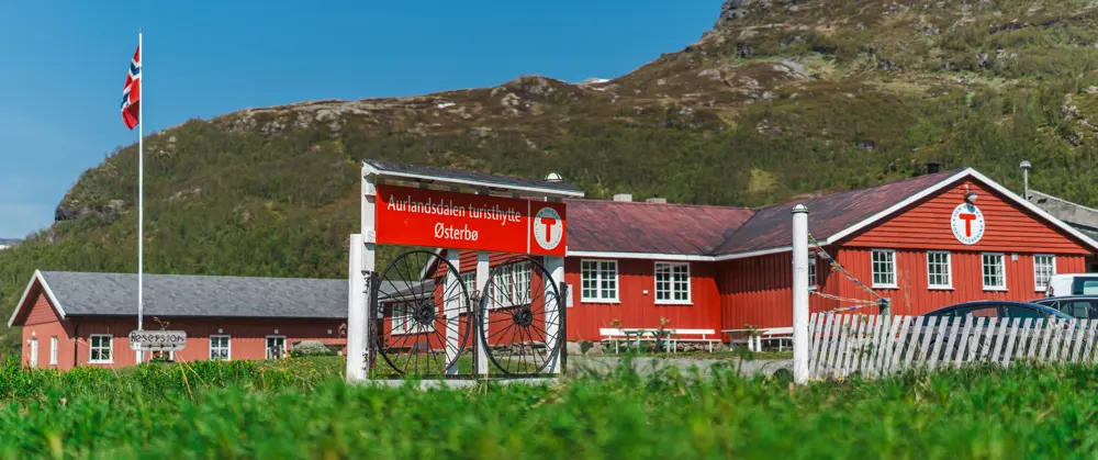 En rødmalt hytte med et skilt hvor det står Aurlandsdalen Turisthytte foran