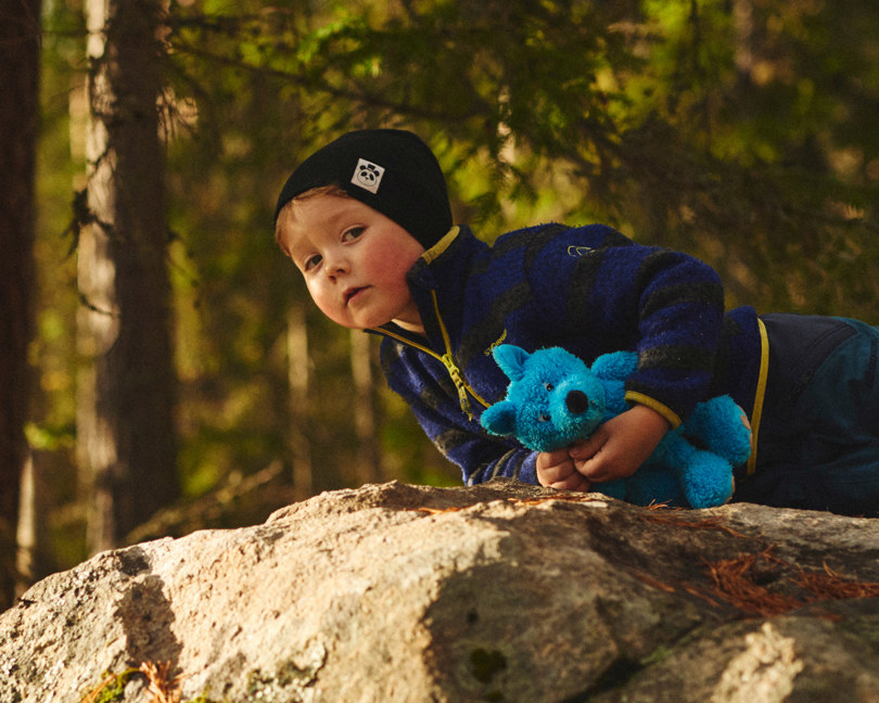En gutt som ligger på en stein og holder en bamse