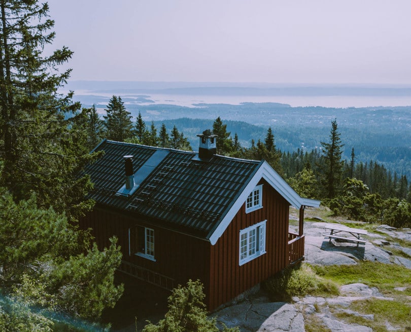 En rødmalt hytte med utsikt utover skogslandskap