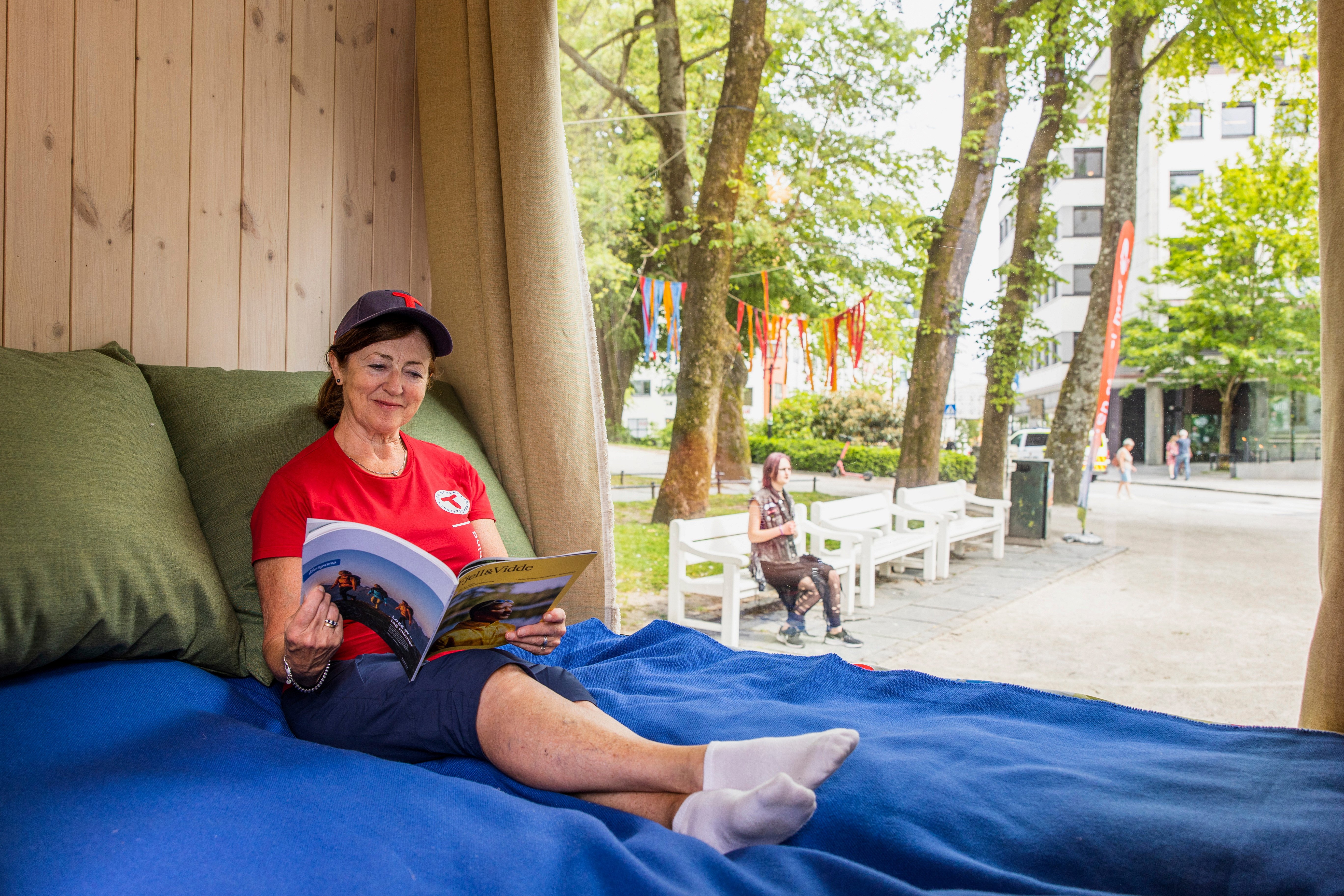 Dame sitter i dobbeltseng p&aring; DNT-hytta p&aring; hjul