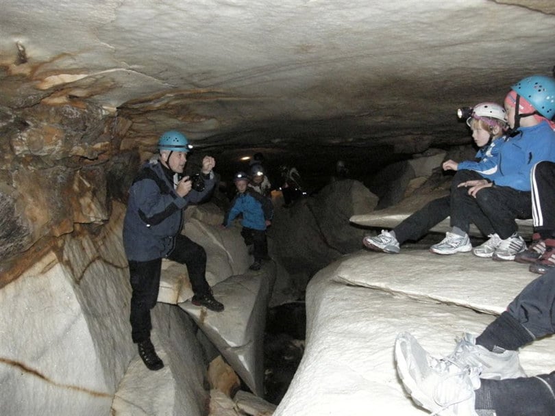 Inne i ei marmorgrotte. En mann med hjelm står i grotta og snakker til en gruppe mennesker som også har hjelm.