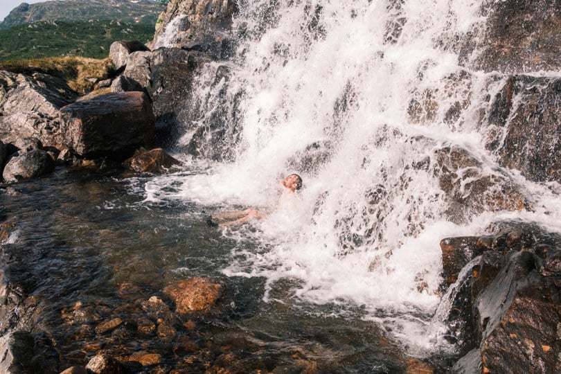 mann som sitter i en liten foss i en elv