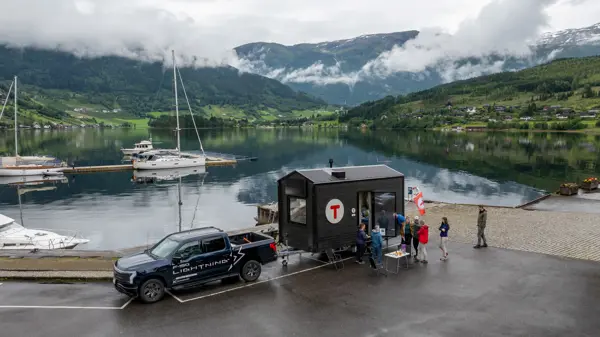 En hytte på hjul står parkert i Ulvik med fjell og fjord bak.