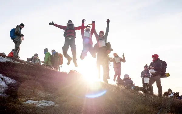 En gruppe ungdommer hopper av glede på en fjelltopp