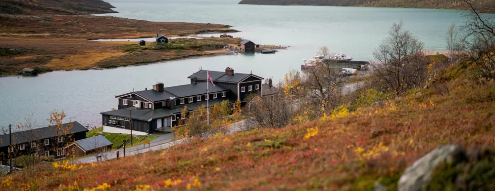 Høstfarger i fjellet rundt en svartmalt hytte