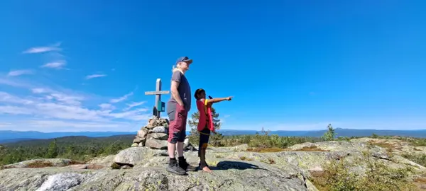 En voksen og et barn står på en fjelltopp og skuer utover