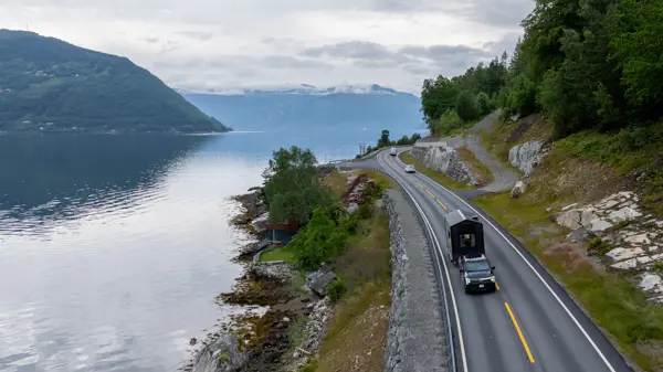 Bil som trekker hytte på henger på vei i vakker natur