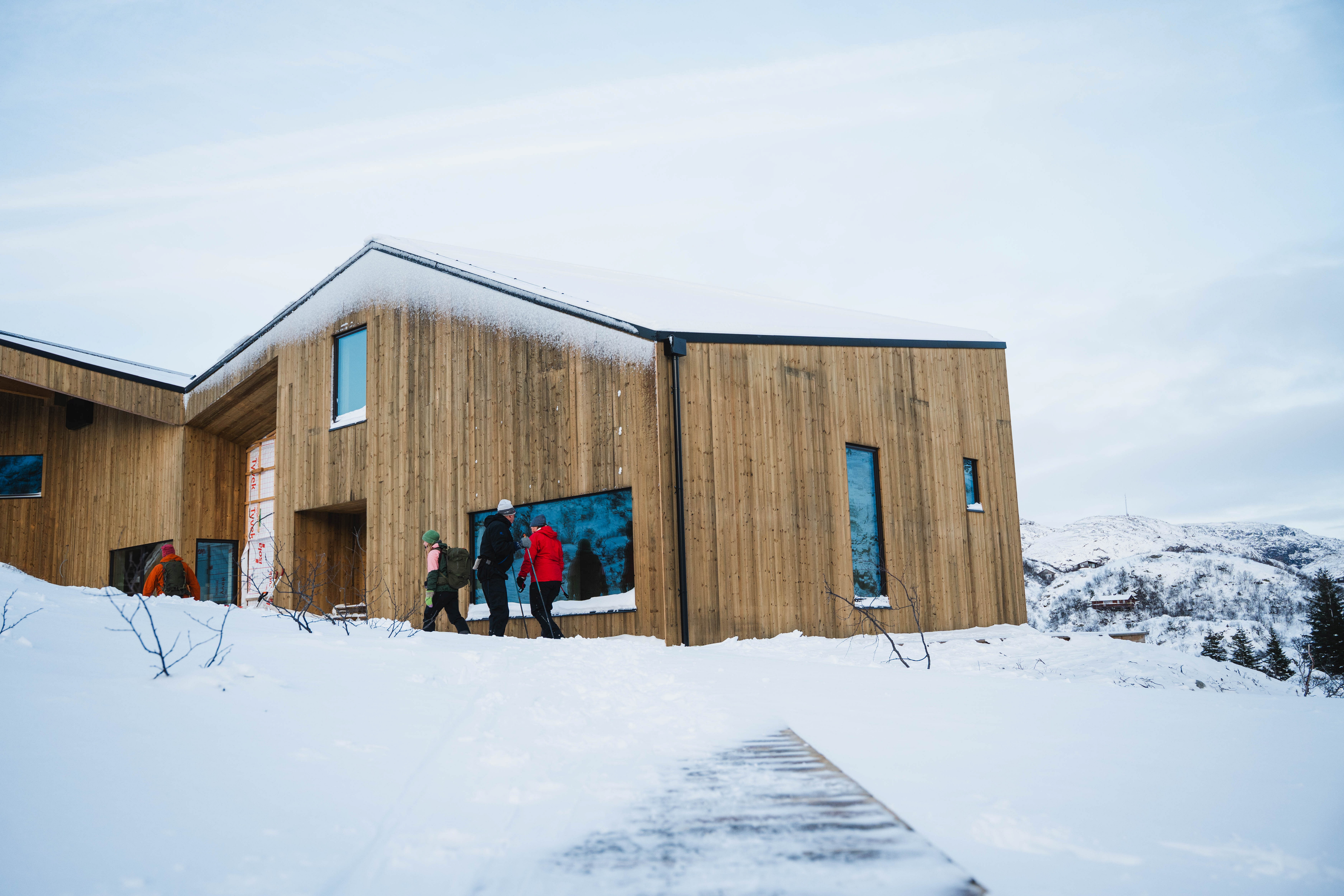 Bilde av en ny hytte som bygges. Tre mennesker titter inn vinduet.