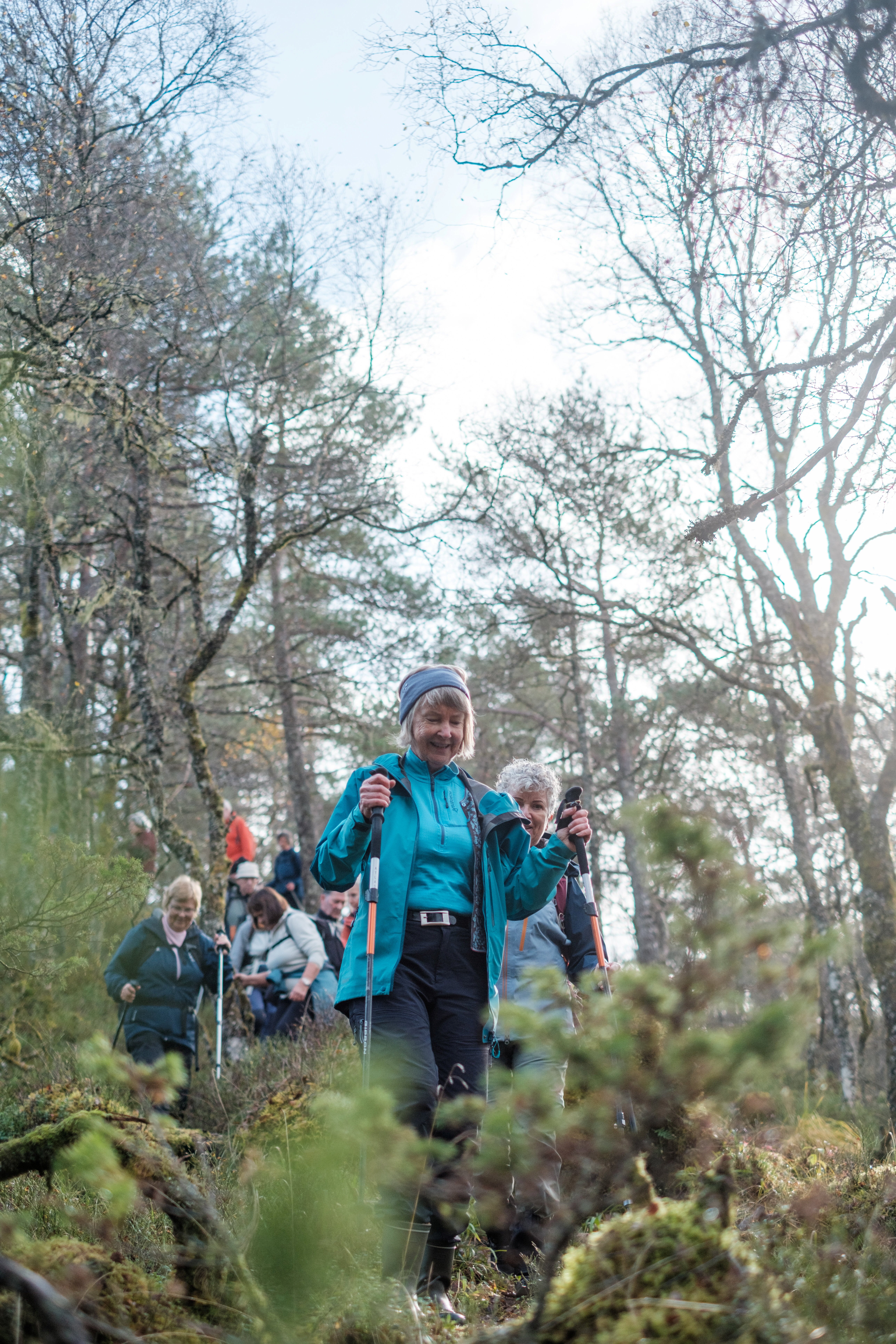 Kvinne g&aring;r med stavar i skogen.