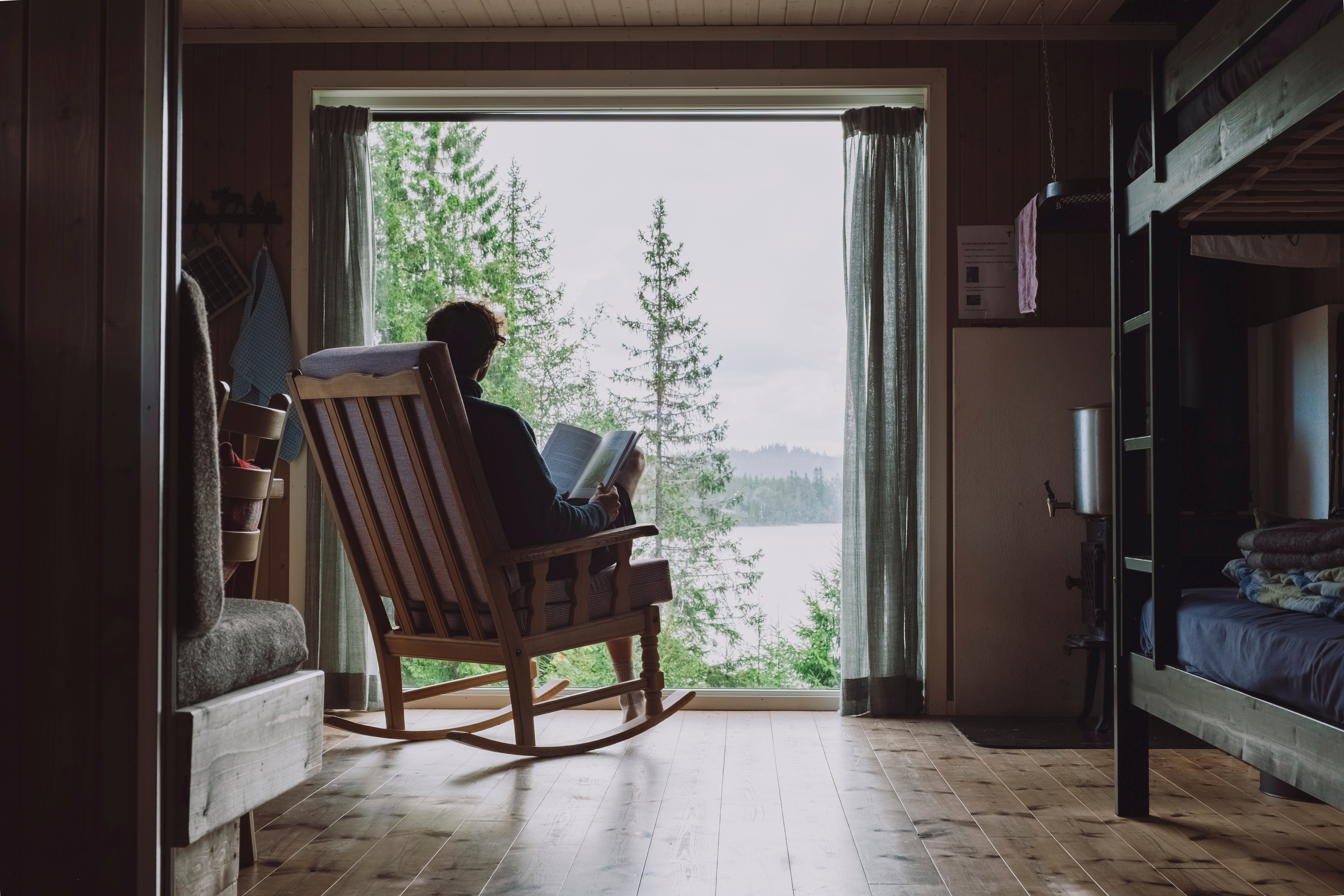 En person som sitter i gyngestol og ser ut et stor vindu.