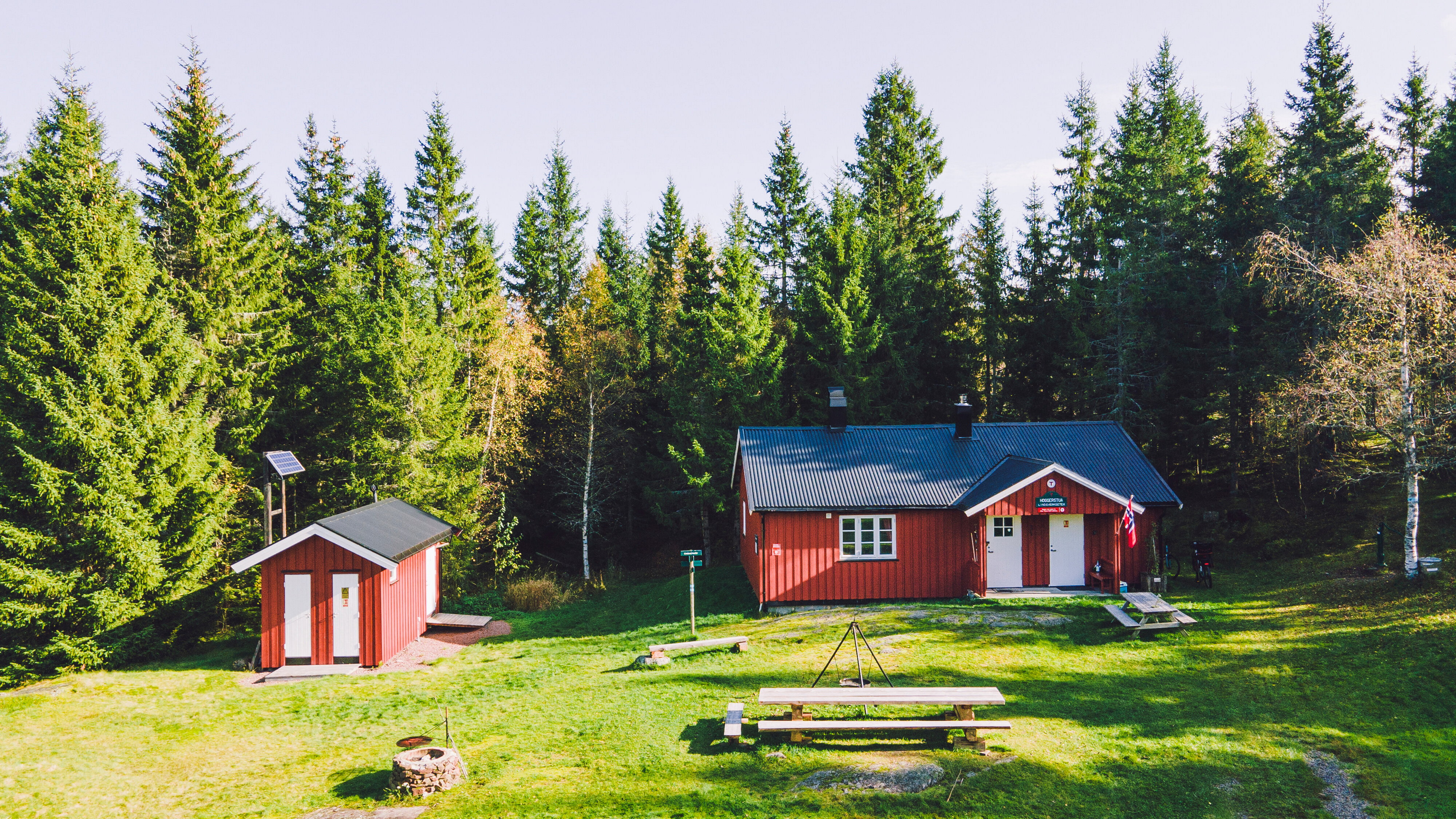 R&oslash;d hytte p&aring; gr&oslash;nn gresslette i skogen