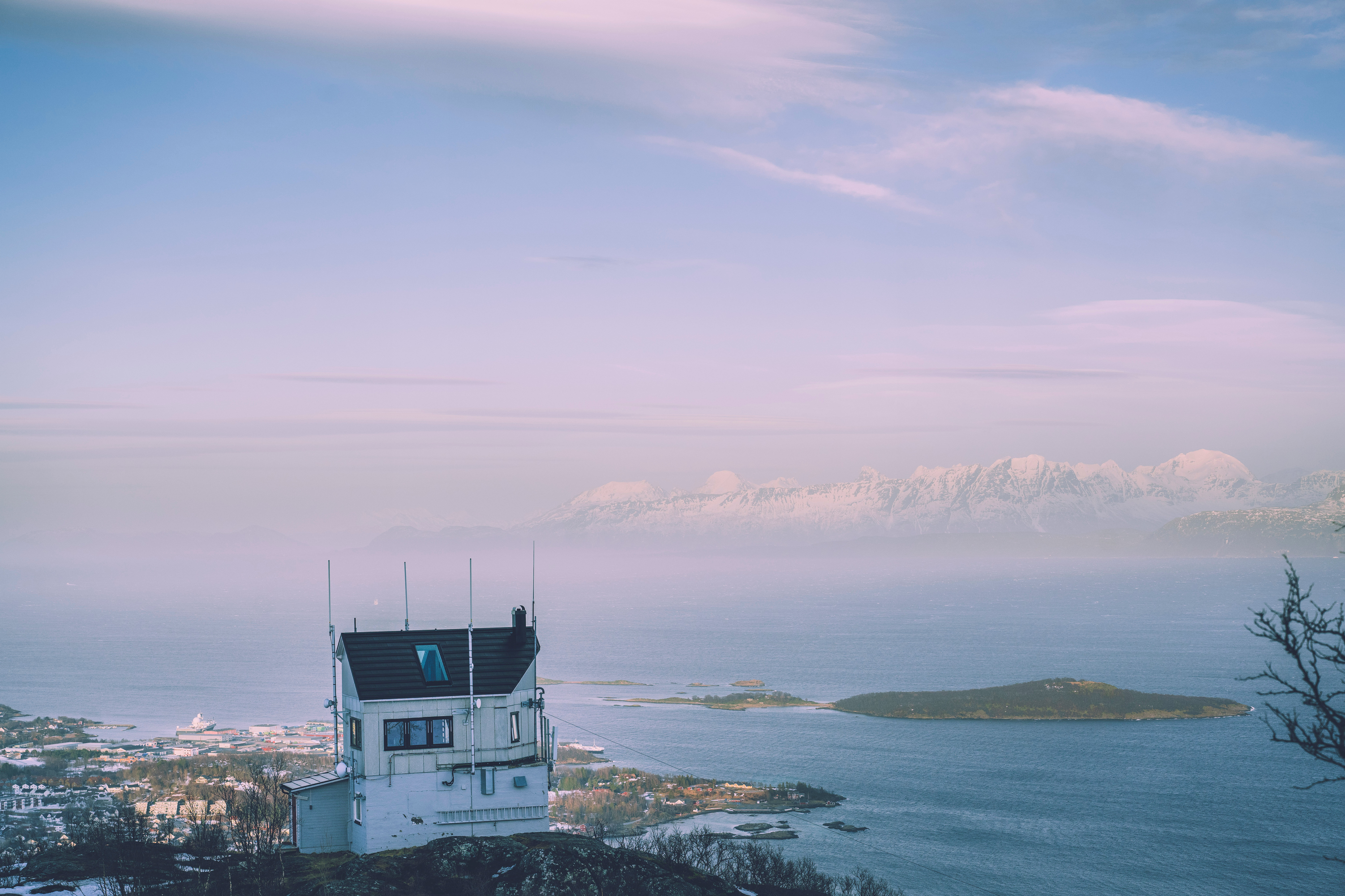 hytte p&aring; fjelltopp med utsikt utover by og fjord