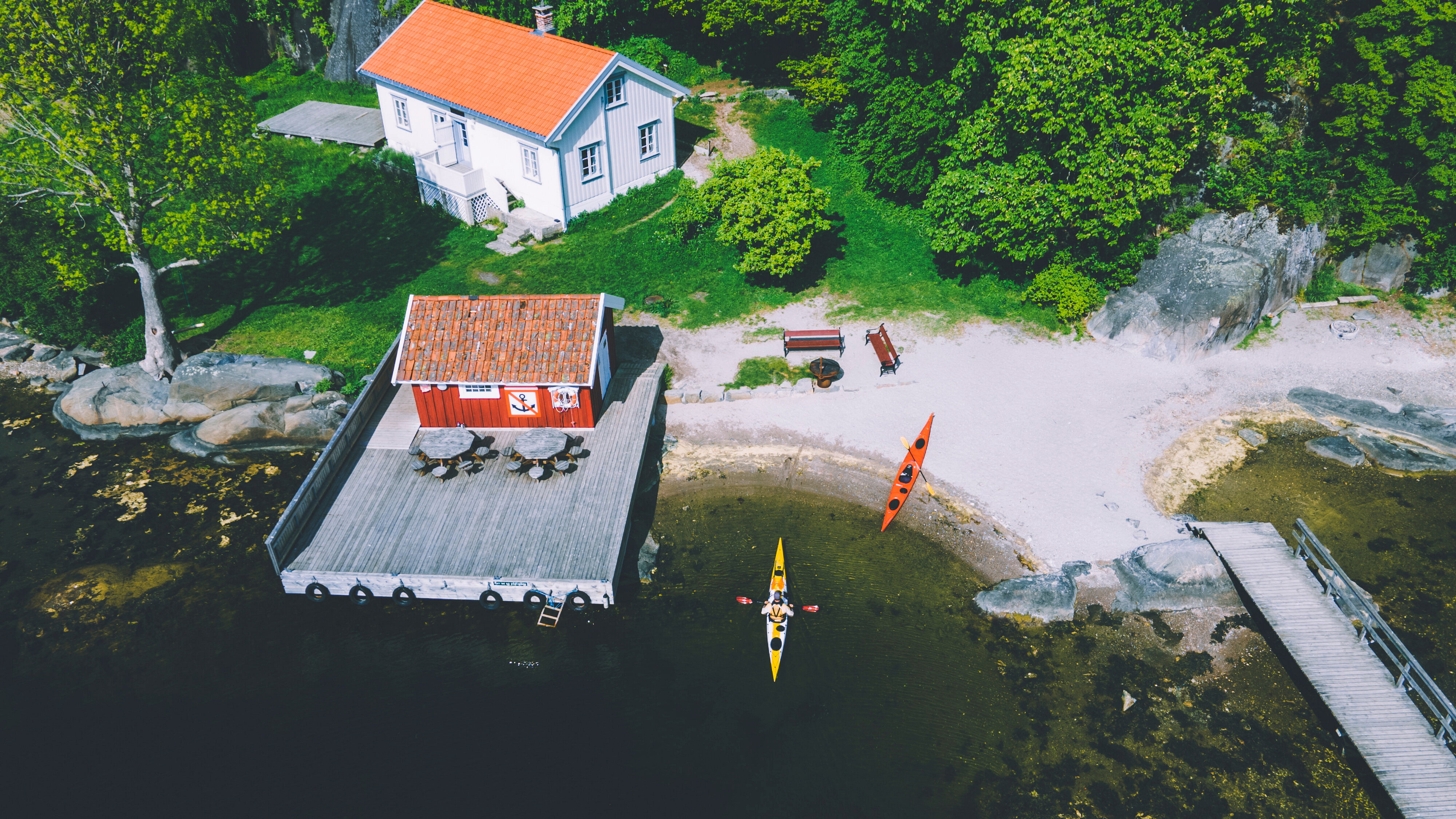 hyggelig hvit s&oslash;rlandshytte i vik med brygge og kajakker