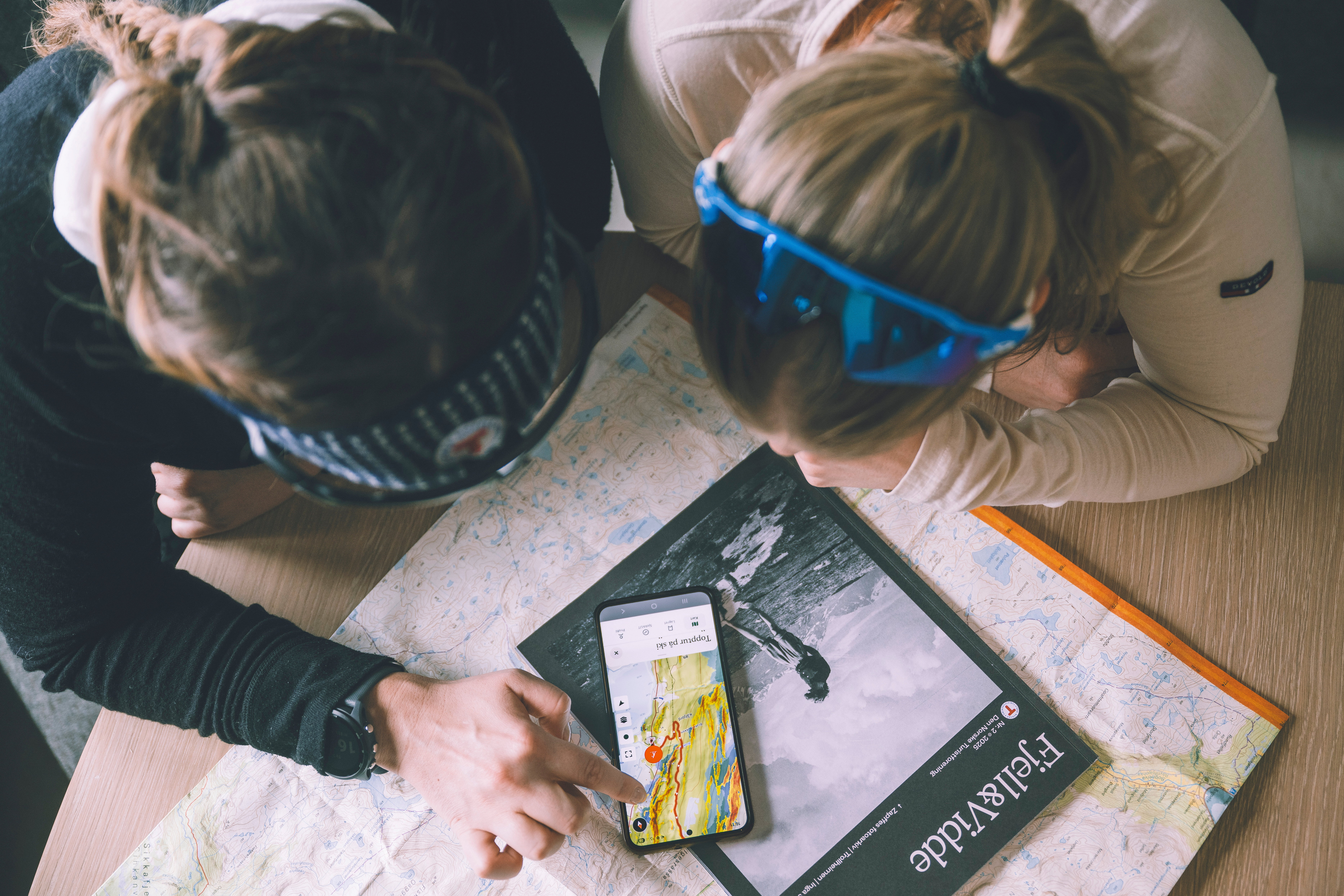 bildet tatt ovenfra hvor to personer seg p&aring; en mobil som ligger p&aring; et bord. 