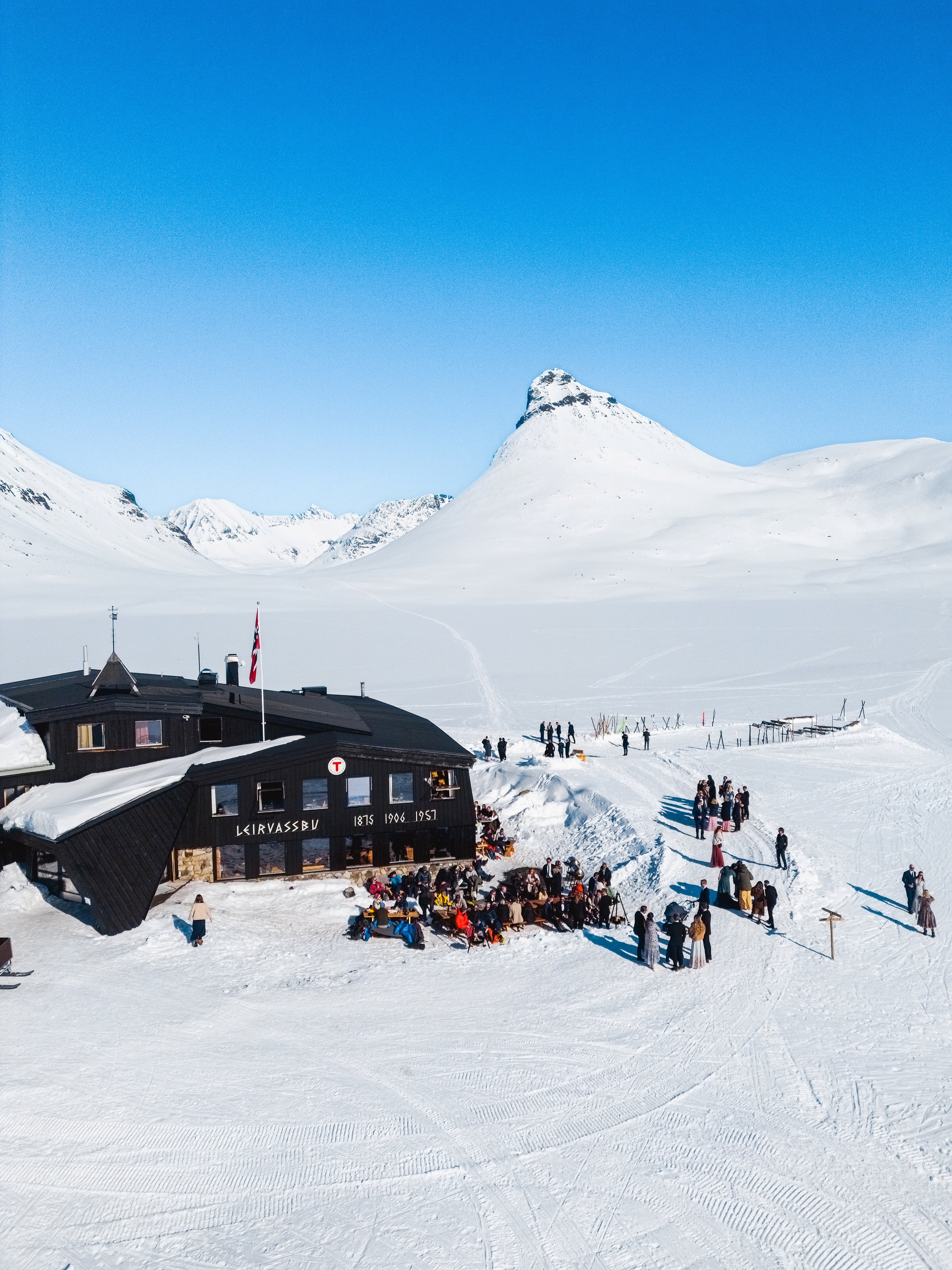 hytte omkranset av sn&oslash;dekte fjell.