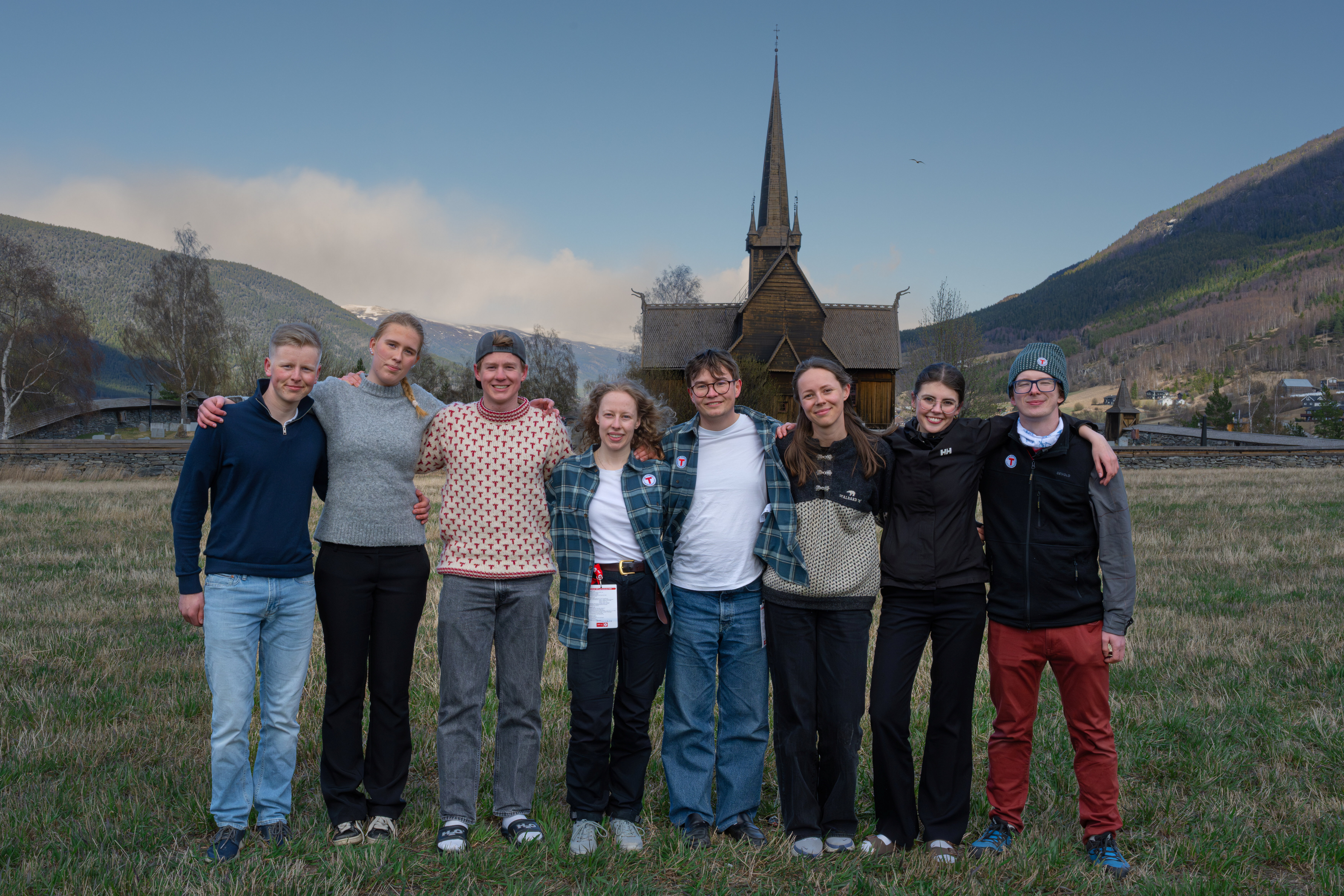 &Aring;tte blide personer foran en stavkirke