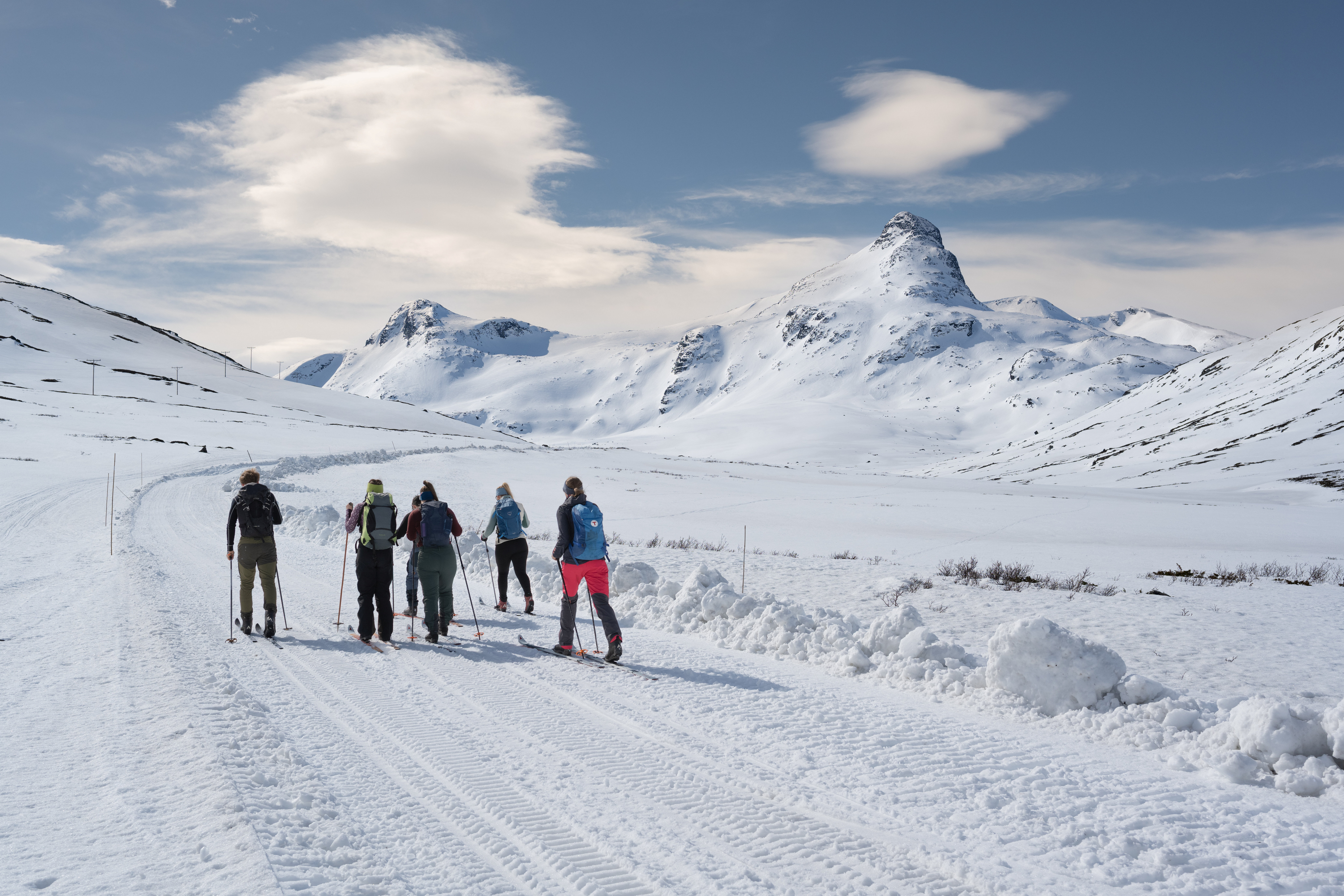 En gruppe mennesker p&aring; fjellski med fjell i bakgrunnen