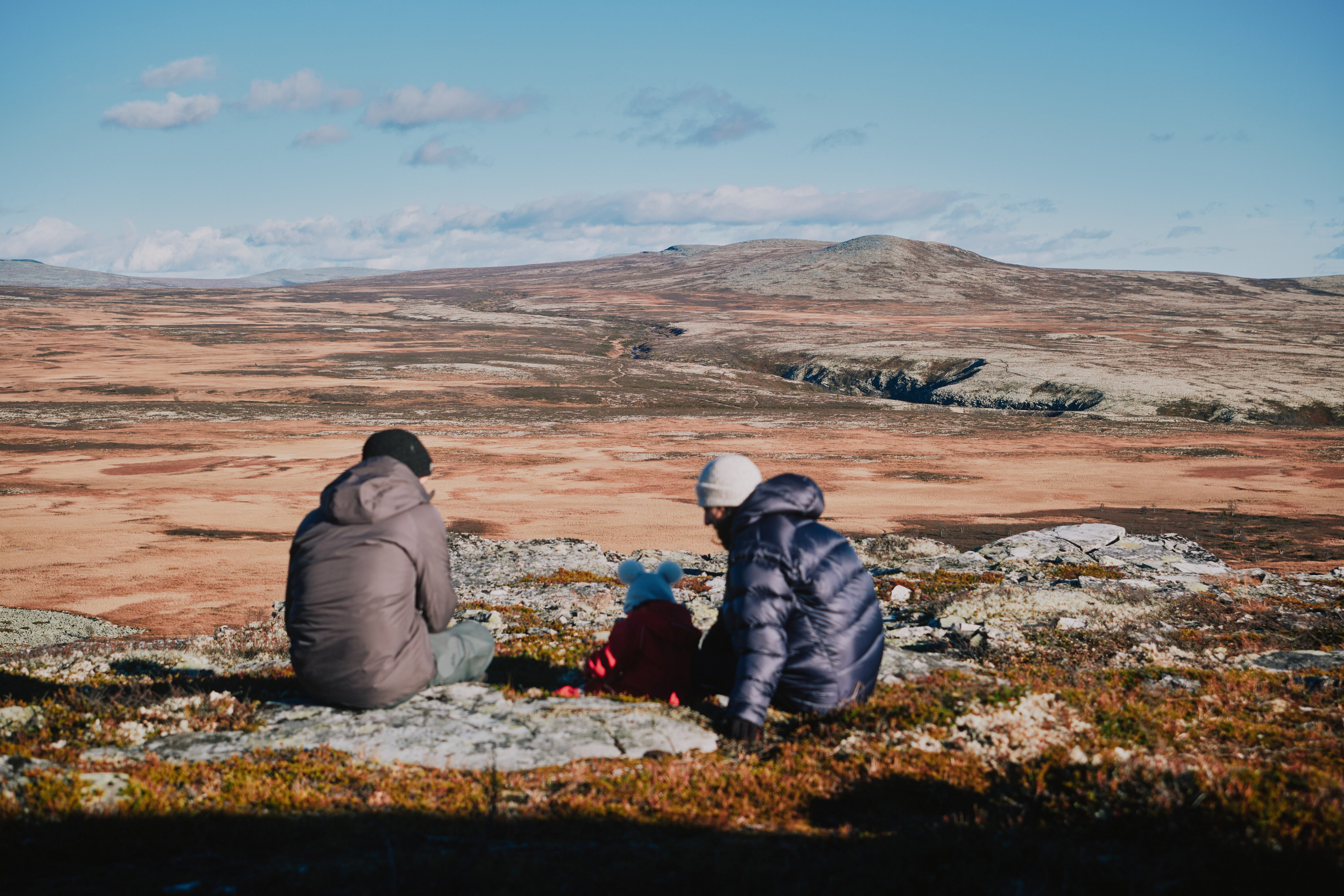 To voksne og baby ser utover vakkert fjellandskap