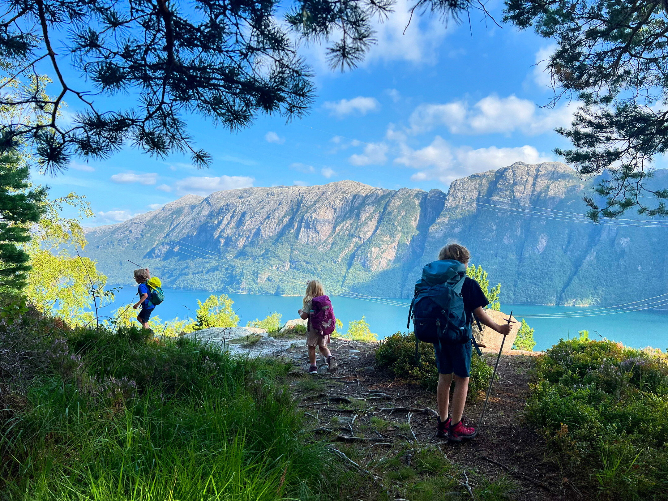 Tre barn g&aring;r p&aring; tur med fjorden foran seg.