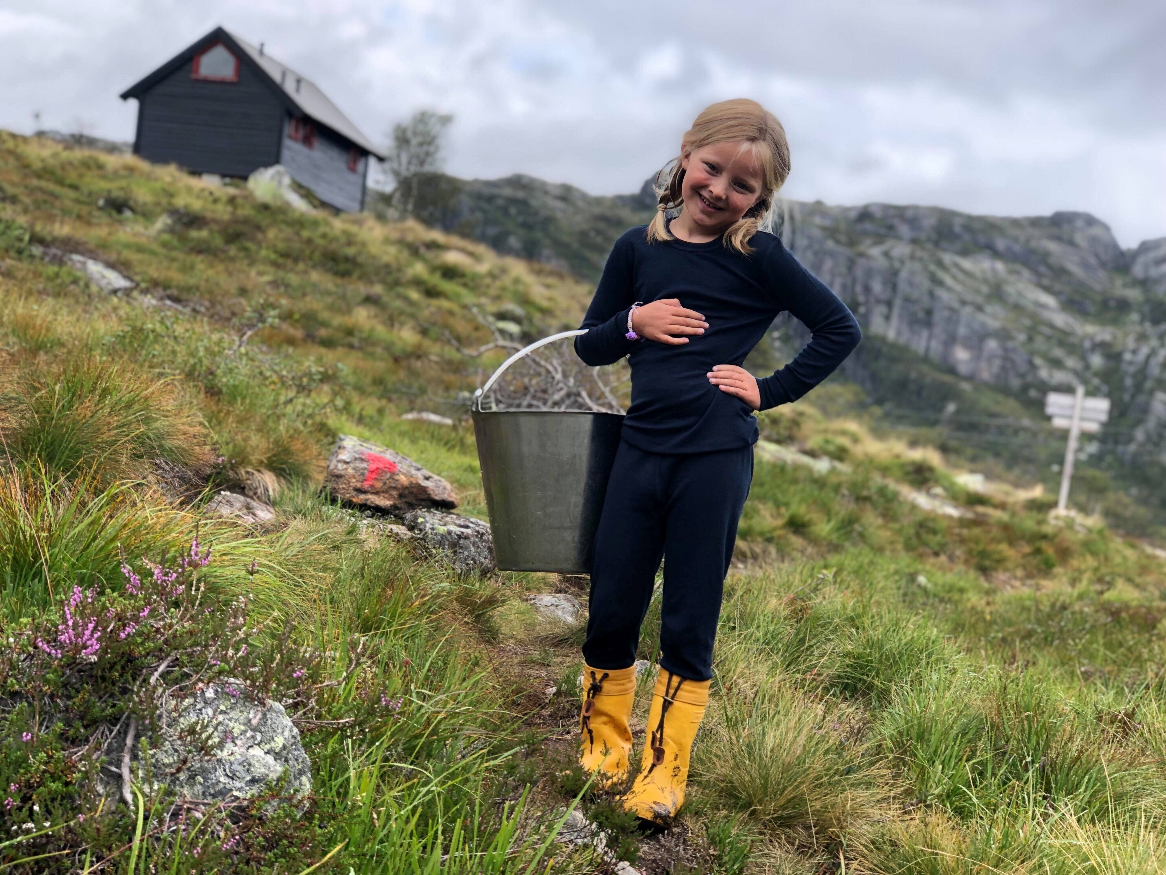 En jente med gule st&oslash;vler holder en b&oslash;tte
