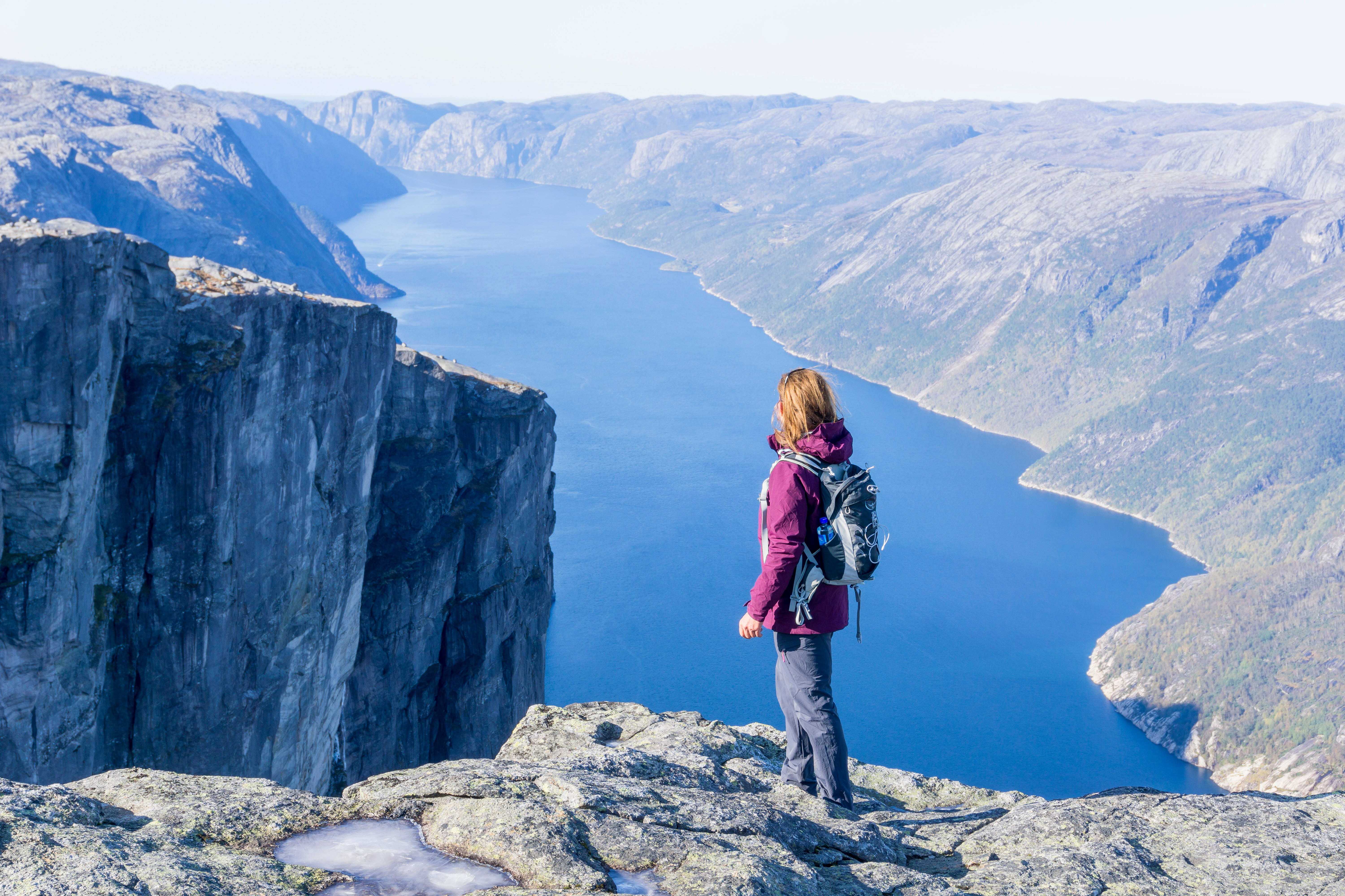 En dame st&aring;r og ser utover en fjord.