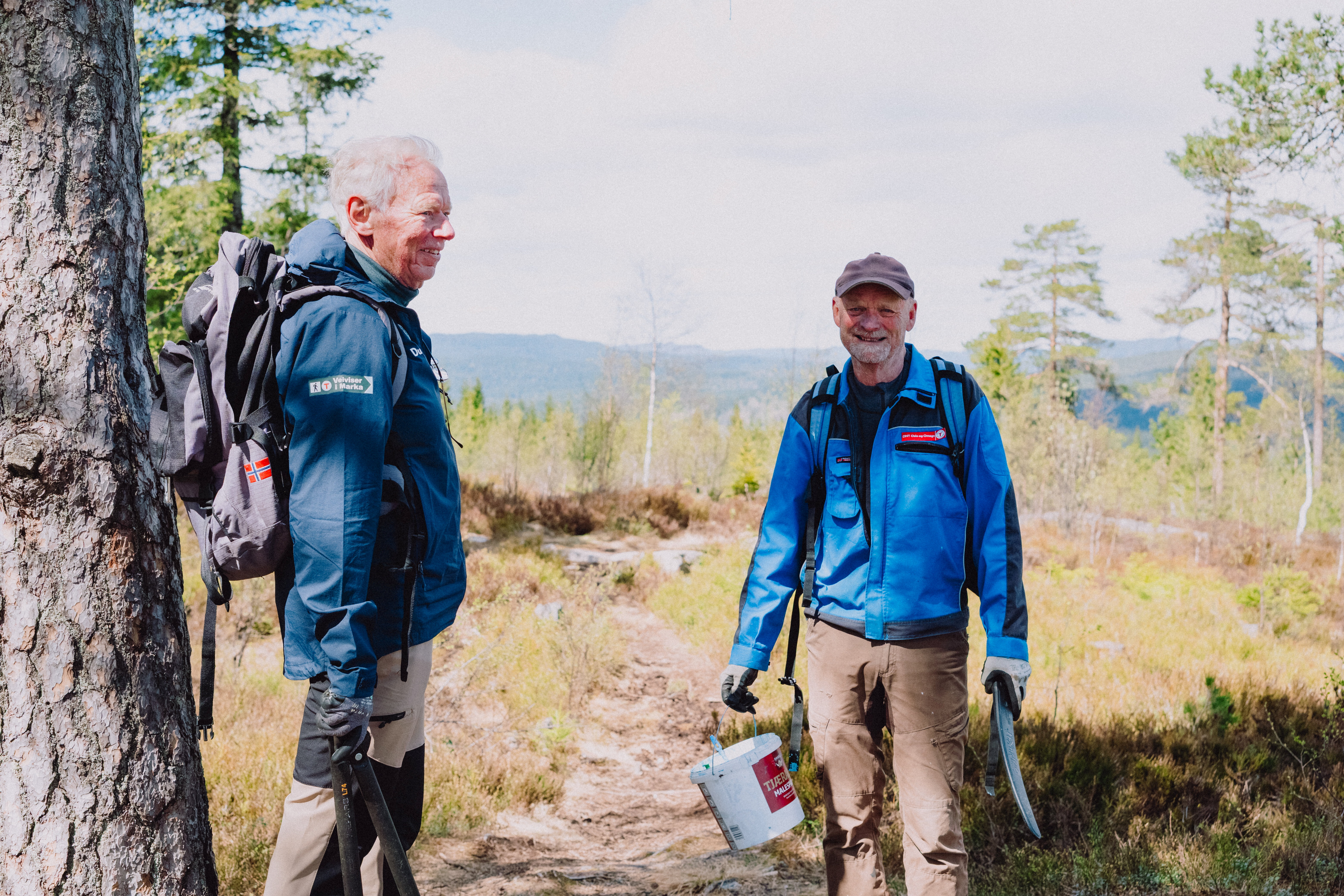 To personer smiler i skogen med utsikt bak