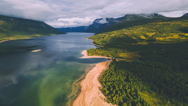 dronebilde av en st&oslash;rre skogs- og innsj&oslash;omr&aring;de. du ser skog, fjell og en sandstrand