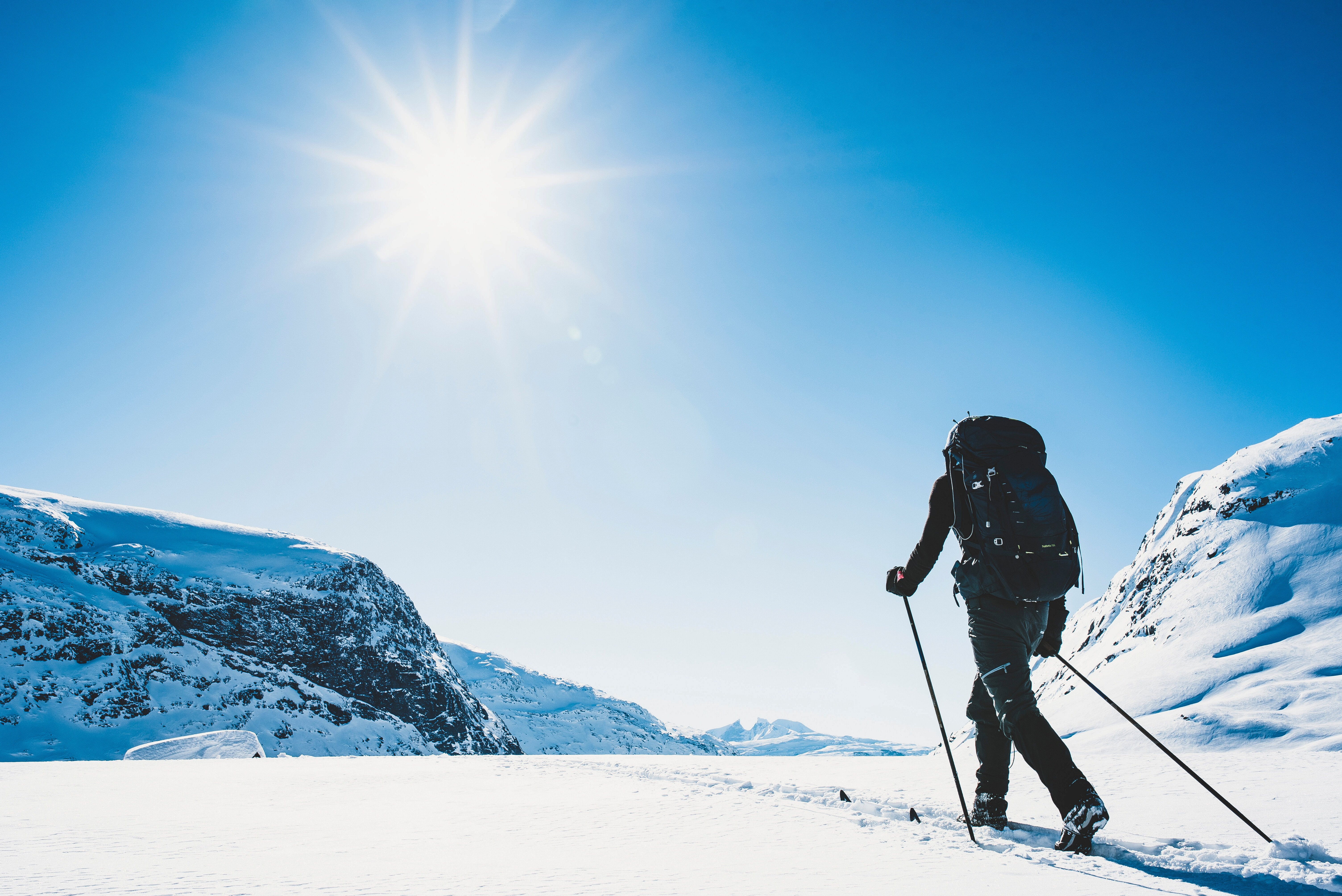 person p&aring; ski som st&aring;r med ryggen til kameraet og har p&aring; seg en stor p&aring; sekk
