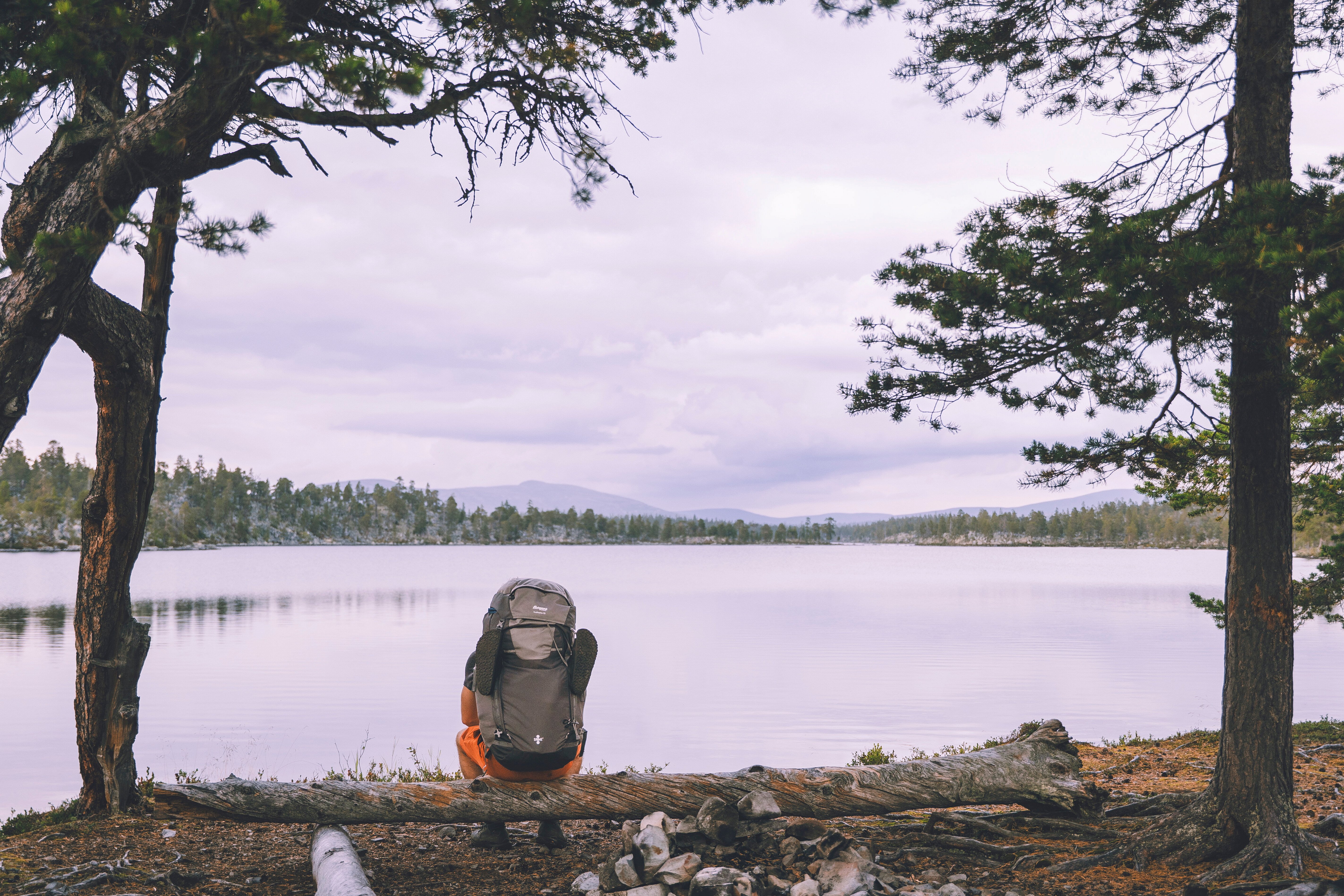 person som sitter med stor sett og ser utover et vann